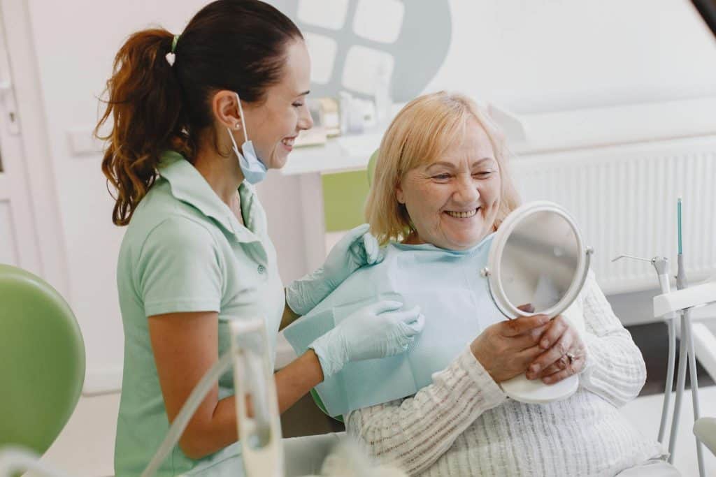 Senior patient at a dental check-up, smiling with the dentist in a modern clinic.